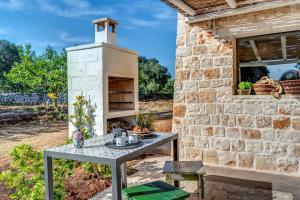 a stone building with a table and a stove at Trulli cicale e olive in Ceglie Messapica