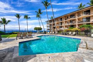 a swimming pool in front of a hotel with palm trees at Kona Makai 3102 in Kailua-Kona