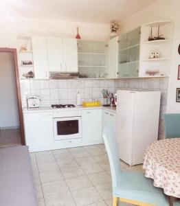 a kitchen with white cabinets and a table and a chair at Babo Apartments in Hvar