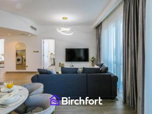 a living room with a blue couch and a tv at Birchfort - Newly Renovated Huge 2 bedroom apartment in Dubai