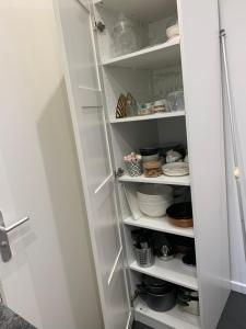 eine weiße Pantryküche mit weißen Regalen und Geschirr in der Unterkunft Charmant appartement - PARIS 18 in Paris