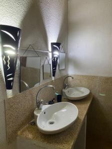 ein Bad mit einem Waschbecken und einem Spiegel in der Unterkunft Case beach in Ngalou Sessène