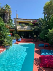 a swimming pool in front of a house at "La Villa Bali", en Bord de Mer à 5 mn des plages avec Piscine à cascade, Grand extérieur unique sur le thème de Bali in Six-Fours-les-Plages