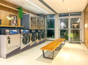 a laundry room with three washing machines and a bench at Apto incrivel a 50m do metro Butanta em Sao Paulo in Sao Paulo