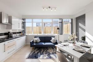 倫敦的住宿－Central Located Apartment in City of London - Farringdon Station，厨房以及带桌子和蓝色沙发的用餐室。