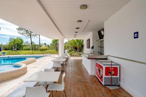 a patio with tables and chairs next to a swimming pool at Apartment Victoria - Quinta do Lago in Quinta do Lago