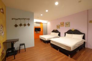 a bedroom with two beds and a desk in it at Bears Line B&B train station in Hualien City