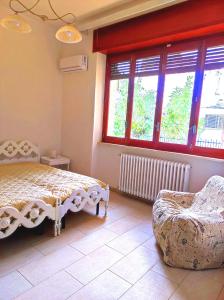 een slaapkamer met een bed, een stoel en ramen bij Villetta Hydro 3 in Bagnolo del Salento