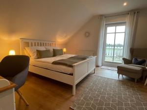 a bedroom with a bed and a window and a chair at Ferienzimmer Claudia in Surwold