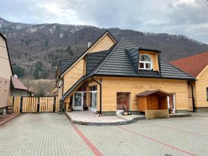 un gran edificio de madera con techo negro en Wellness Penzión Rosnička, en Kraľovany