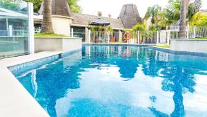a swimming pool with blue water in front of a house at Holiday Inn Auckland Airport by IHG in Auckland