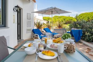 a table with plates of food and an umbrella at Casa Alessa - Vale de Lobo in Almancil