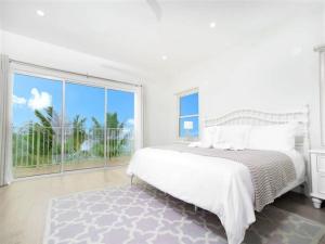 a white bedroom with a bed and a large window at Azure Breeze # 6 in North Side