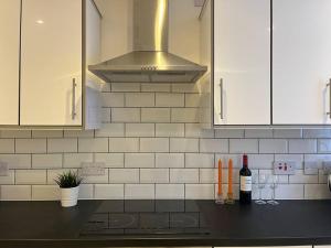 a kitchen with white cabinets and bottles of wine at Lavender house, beautiful central townhouse in Leamington Spa