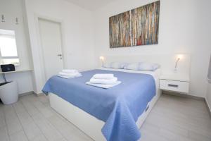 a white bedroom with a blue bed with towels on it at Luxury Apartment Marko in Promajna