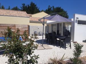 une terrasse avec une table et un parasol dans l'établissement Cale 32 - Chambres d'hôtes, à Saint-Jean-de-Monts