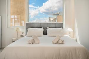 a bedroom with a white bed with a large window at Olvar's Modern Luminous Suite , Athens Downtown in Athens