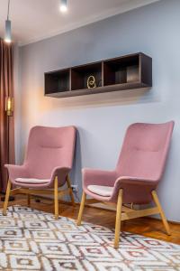 twee roze stoelen in een kamer met een tapijt bij Apartament Nordic in Gura Humorului