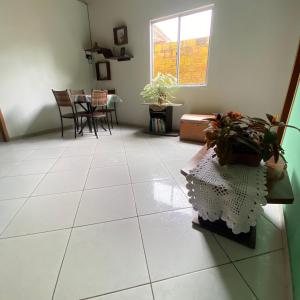 uma sala de estar com piso em azulejo branco e uma mesa com plantas em Lazer Hostel em Barreirinhas