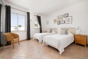 a bedroom with two beds and a chair and a window at Casa Maya - Vale do Garrão in Quinta do Lago