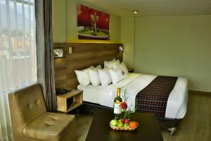 Una habitación de hotel con una cama y una mesa con una botella de vino en Terramística Arequipa - Monasterio, en Arequipa