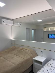 una camera con un letto e un grande specchio di Apartamento Centro Vitta Boulevard a Gramado