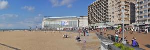 a group of people walking on a beach next to buildings at Casa Casino Oostende in Ostend