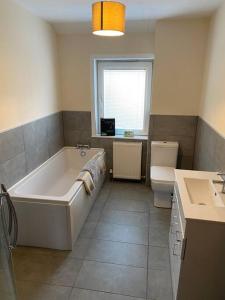 a bathroom with a tub and a toilet and a sink at 7 BR for 10 people in town in Stornoway