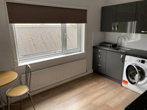 a kitchen with a washing machine and a window at 7 BR for 10 people in town in Stornoway
