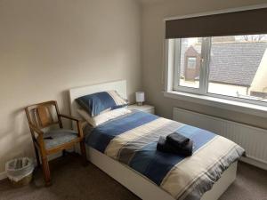 a bedroom with a bed and a chair and a window at 7 BR for 10 people in town in Stornoway