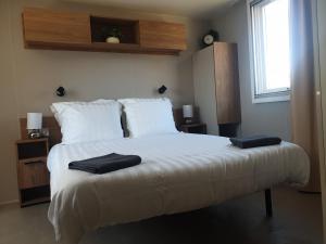 1 dormitorio con 1 cama blanca y 2 toallas en MH Luxury Eden Mar Estang Plage 100m 2TV 2 Sdb Baby confort Plus en Canet-en-Roussillon