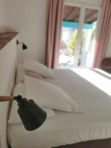 a black lamp on a white bed with a window at L'auberge Camarguaise in Saintes-Maries-de-la-Mer