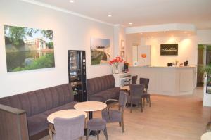 a waiting room with couches and tables and a kitchen at Hotel Ambrosia in Ieper