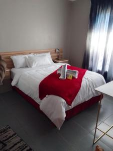 una camera da letto con un grande letto con una coperta rossa di The Success Guest House a Standerton