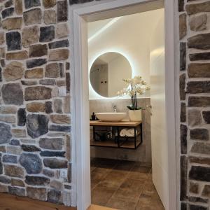 bagno con parete in pietra e lavandino di Olivea Luxury Suites a Fažana