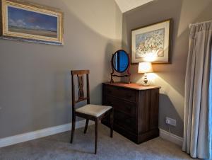 a room with a chair and a mirror and a dresser at The Stables at Lorum Old Rectory in Bagenalstown