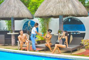 a group of people sitting around a pool at a resort at Blue Moon Inn in Dauis