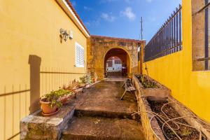 a yellow building with a hallway with potted plants at Flatguest Villa Mayca in Santa Brígida