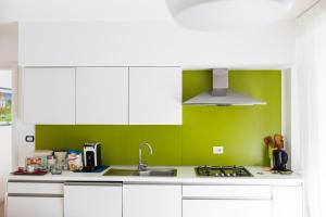 a kitchen with white cabinets and a green wall at B&B Samarelle - Exclusive Villa in Molfetta
