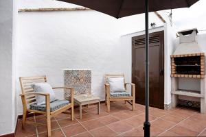 un patio con 2 sillas y una sombrilla en Estudio Clara 1, en Conil de la Frontera