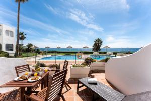 ミハスにあるSeafront Beach house Rocas del Marのテーブルと椅子とプールのあるパティオ