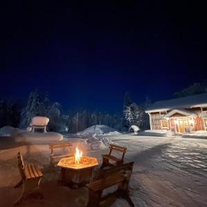 un foyer extérieur dans la neige la nuit dans l'établissement Taiga Forest Lodge, à Gällivare