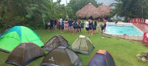 a group of people standing in the grass next to tents at Cabaña la Hamaca Grande un encuentro con la naturaleza in El Zaino