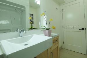 a white bathroom with a sink and a mirror at Beautiful 1 Bedroom Garden Suite in Metrotown in Burnaby
