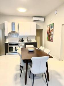 Una cocina con una mesa de madera y sillas blancas. en Luxurious Beachside 3-Br Apt, en San Juan