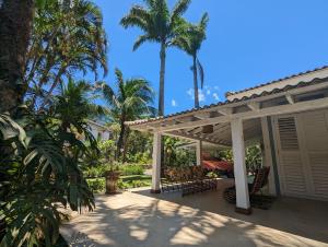 um pátio com uma pérgola e palmeiras em Linda Casa Praia de Pauba em condominio em São Sebastião