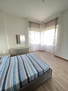 a bedroom with a bed in a room with windows at Trilo Conero, in residence con piscina ed aria condizionata vicino al mare in Marcelli