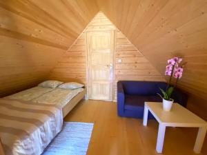 a bedroom with a bed and a chair in a attic at Domki z bali Deluxe in Jarosławiec