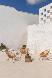 a patio with three chairs and a table with flowers at Antica Masseria San Benedetto in Ostuni