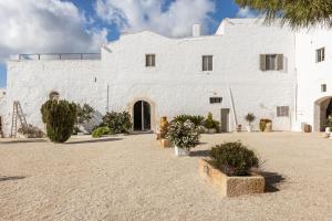 a white building with plants in front of it at Antica Masseria San Benedetto in Ostuni